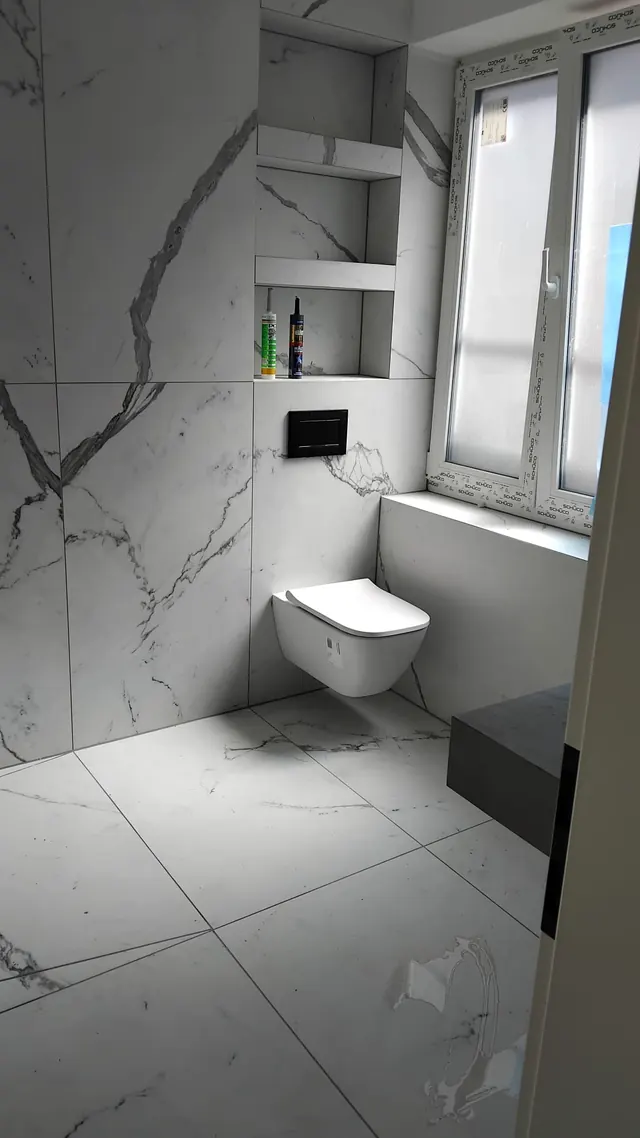 Wand-WC mit eingebauter Ablagenische im Bad mit Marmoroptik-Fliesen