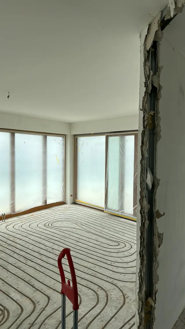 Wohnzimmer mit eingefräster Fußbodenheizung vor einer Eckfensterfront